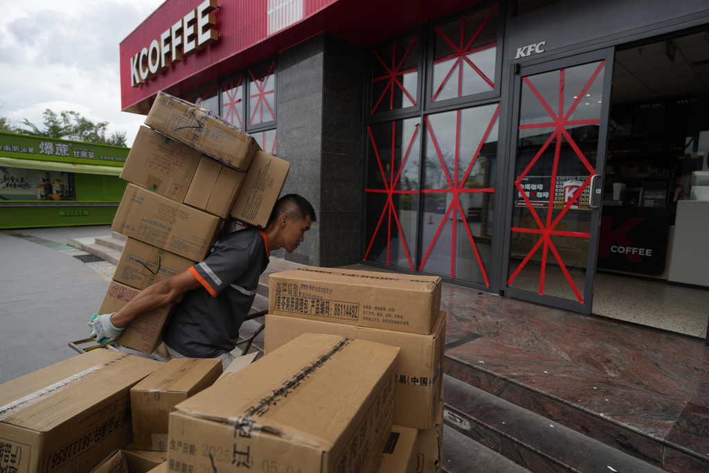 A delivery man carries goods into a restaurant with its windows taped protectively against strong winds ahead of Super Typhoon Ragasa in Shenzhen in southern China's Guangdong province on Tuesday, Sept. 23, 2025. (AP Photo/Ng Han Guan)