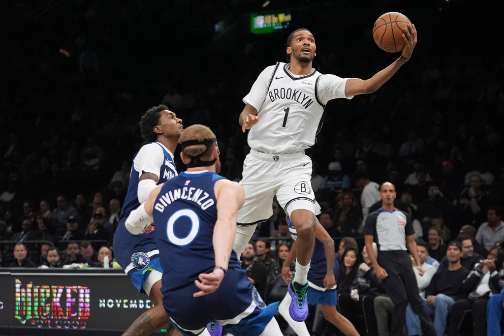 Brooklyn Nets' Ziaire Williams (1) drives past Minnesota Timberwolves' Donte DiVincenzo (0) and Jaden McDaniels (3) during the first half of an NBA basketball game Monday, Nov. 3, 2025, at Barclays Center in New York. (AP Photo/Frank Franklin II)