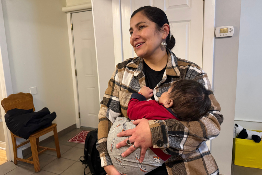 Feliza Martinez, a U.S. citizen and volunteer, holds a 5-month-old baby at a Minneapolis safe house Friday, Jan. 16, 2026, after his mother was detained by immigration agents. (AP Photo/Jack Brook)
