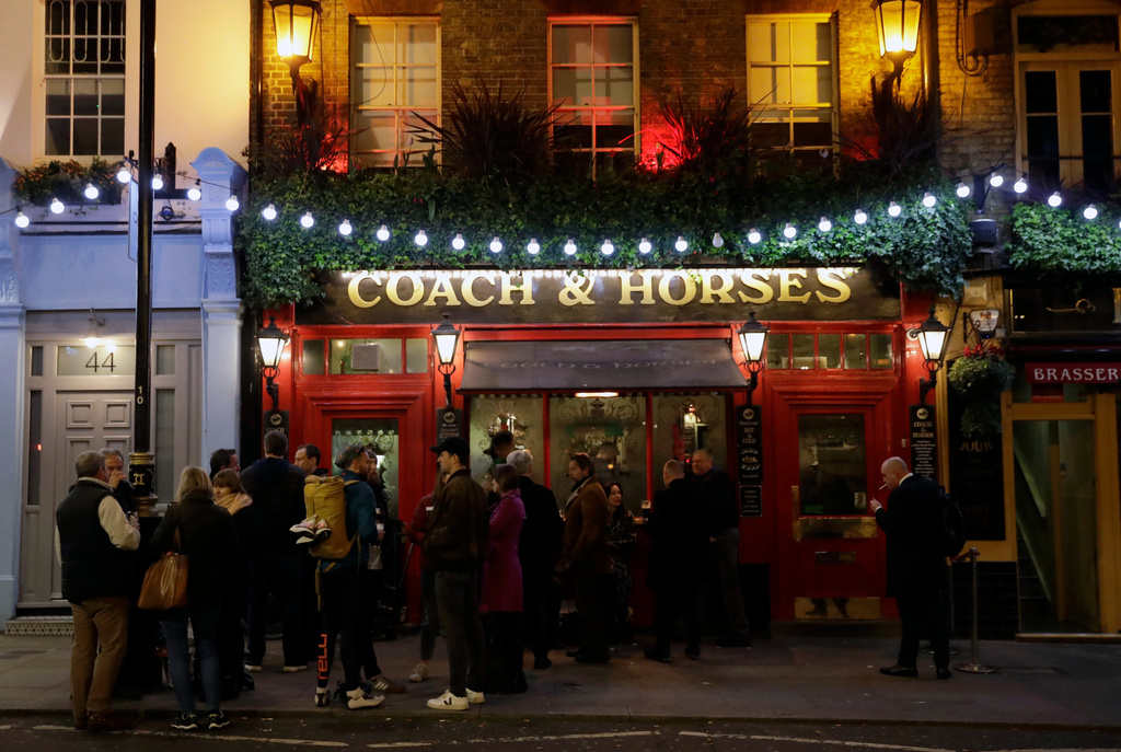 FILE - People stand drinking outside the Coach & Horses pub on Saint Patrick's Day in the Covent Garden district of central London, which is a popular tourist area, Tuesday, March 17, 2020. (AP Photo/Matt Dunham, file)