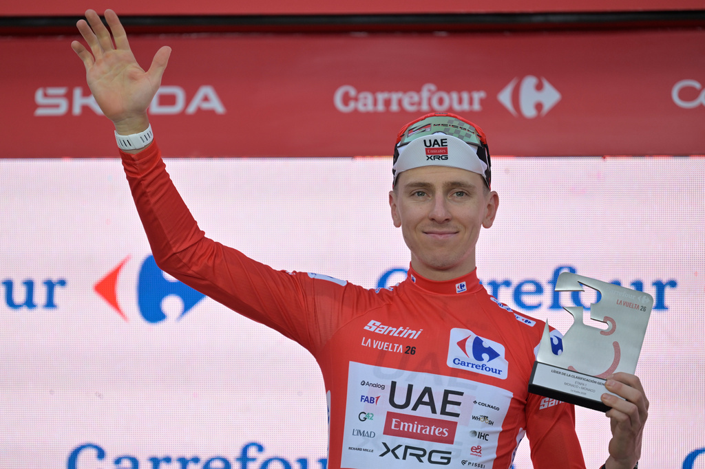 Slovenia's Tadej Pogacar, wearing the overall leader's red jersey celebrates on the podium after winning the first stage of the La Vuelta cycling race, a time trial with start and finish in Monaco, Saturday, Aug. 22, 2026. (AP Photo/Philippe Magoni)
