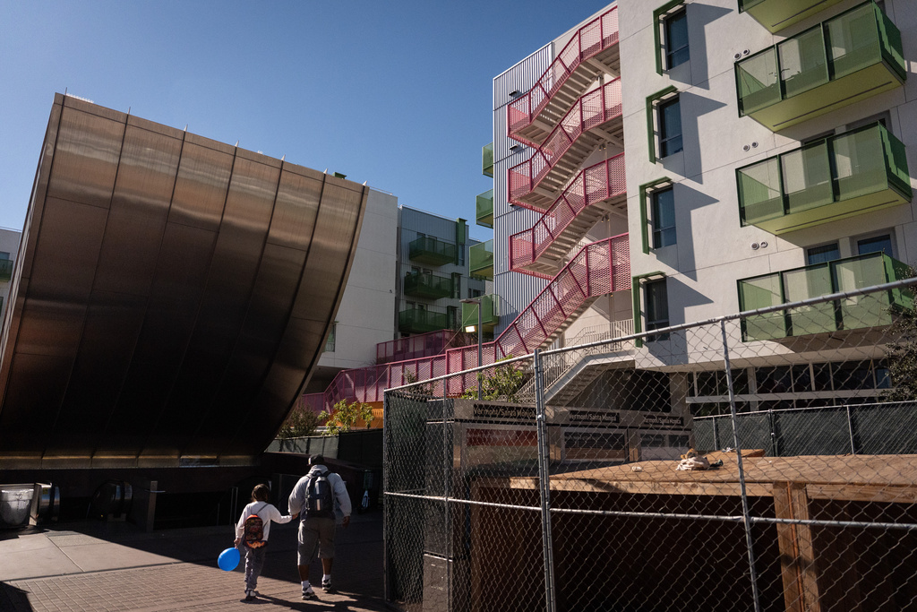 A family arrives at a metro station next to the Santa Monica and Vermont Apartments in Los Angeles, Monday, Nov. 10, 2025. (AP Photo/Jae C. Hong)