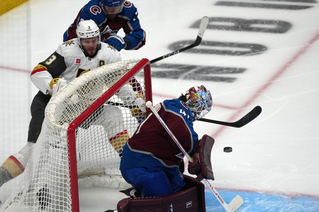 Vegas Golden Knights defenseman Brayden McNabb, bottom left, shoots against Colorado Avalanche goaltender Scott Wedgewood, right, after driving past defenseman Brett Kulak, top left, during the third period in Game 2 of the Western Conference finals NHL hockey Stanley Cup playoff series Friday, May 22, 2026, in Denver. (AP Photo/David Zalubowski)