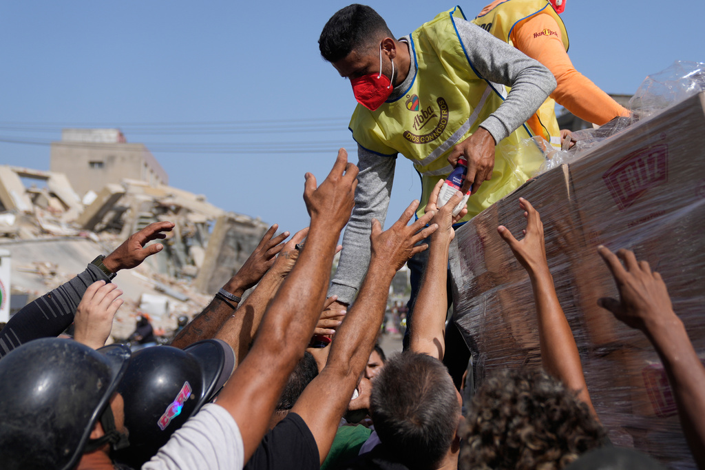 Members of a religious organization distribute food to people affected two days after an earthquake struck La Guaira, Venezuela, Friday, June 26, 2026. (AP Photo/Ariana Cubillos)