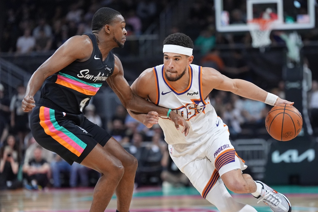 Phoenix Suns guard Devin Booker (1) drives against San Antonio Spurs guard De'aaron Fox (4) during the first half of an NBA basketball game in Austin, Texas, Thursday, Feb. 19, 2026. (AP Photo/Eric Gay)