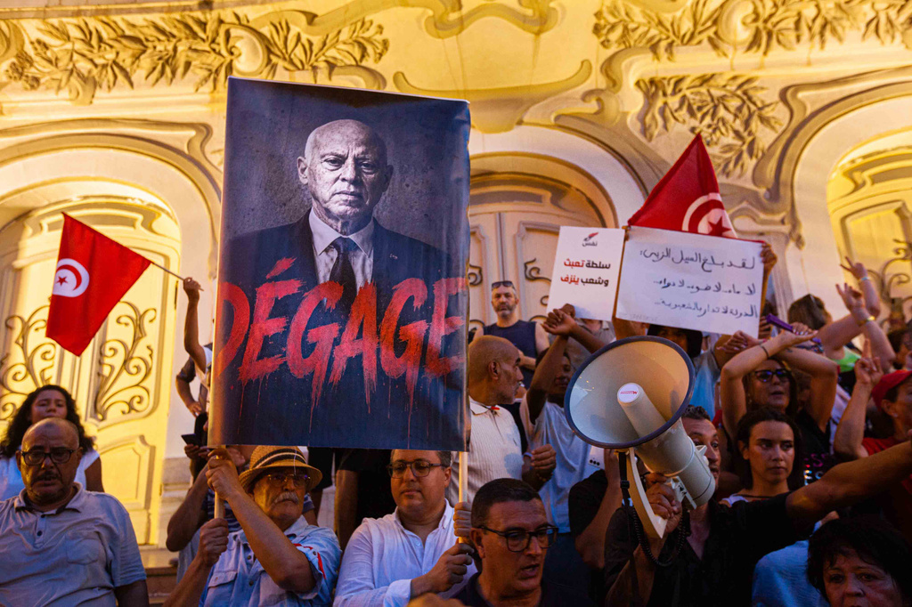 People take part in a protest against rising prices, declining purchasing power and shortages of basic goods in Tunis, Tunisia, Thursday, Aug. 20, 2026. Banner in French showing Preident Kais Saied reads "Leave". (AP Photo/Ons Abid)