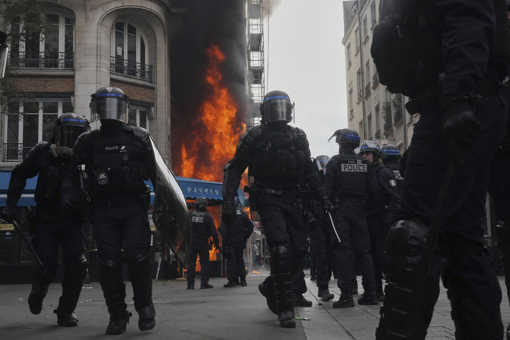Riot police officers take position in front of a burning restaurant during the « Bloquons Tout » (Block Everything) protest movement in Paris, France, Wednesday, Sept. 10, 2025. (AP Photo/Thibault Camus)
