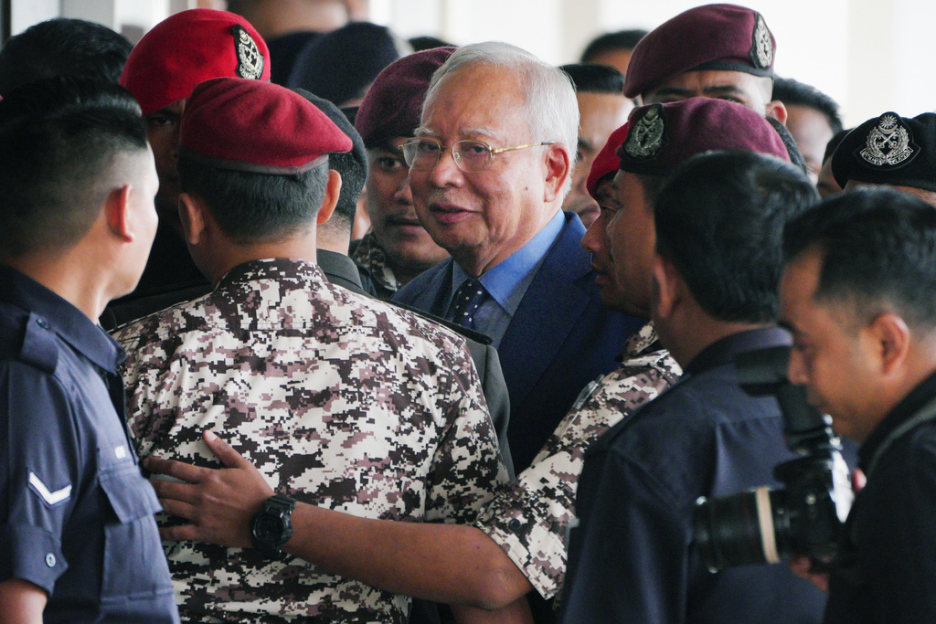 FILE - Malaysian former Prime Minister Najib Razak, center, is escorted by prison officers on his arrival at the Kuala Lumpur High Court complex in Kuala Lumpur, Malaysia, Oct. 30, 2024. (AP Photo/Vincent Thian, File)