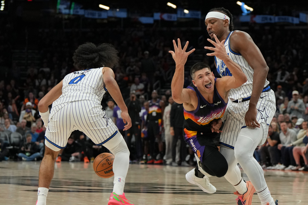 Phoenix Suns guard Grayson Allen reacts after loosing the ball in between Orlando Magic guard Anthony Black (0) and center Wendell Carter Jr. during the second half of an NBA basketball game, Saturday, Feb. 21, 2026, in Phoenix. (AP Photo/Rick Scuteri)