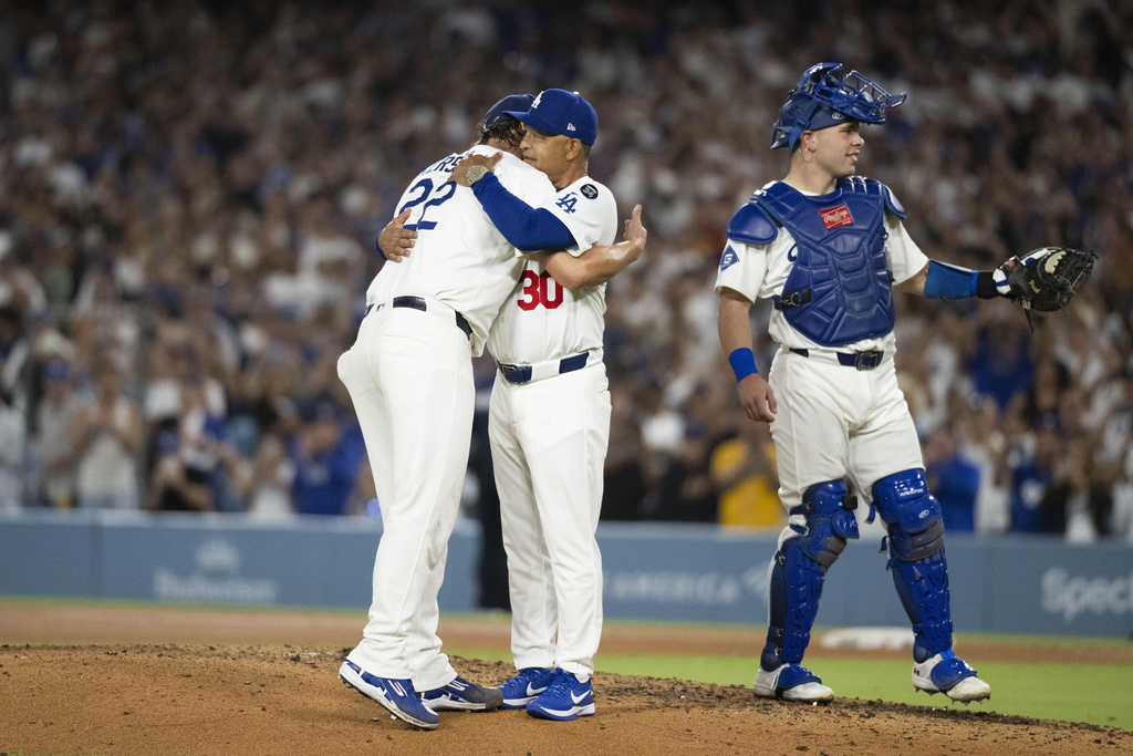 Los Angeles Dodgers starting pitcher Clayton Kershaw, left, hugs manager Dave Roberts, center, after being removed during the fifth inning of a baseball game against the San Francisco Giants, in Los Angeles, Friday, Sept. 19, 2025. (AP Photo/Kyusung Gong)