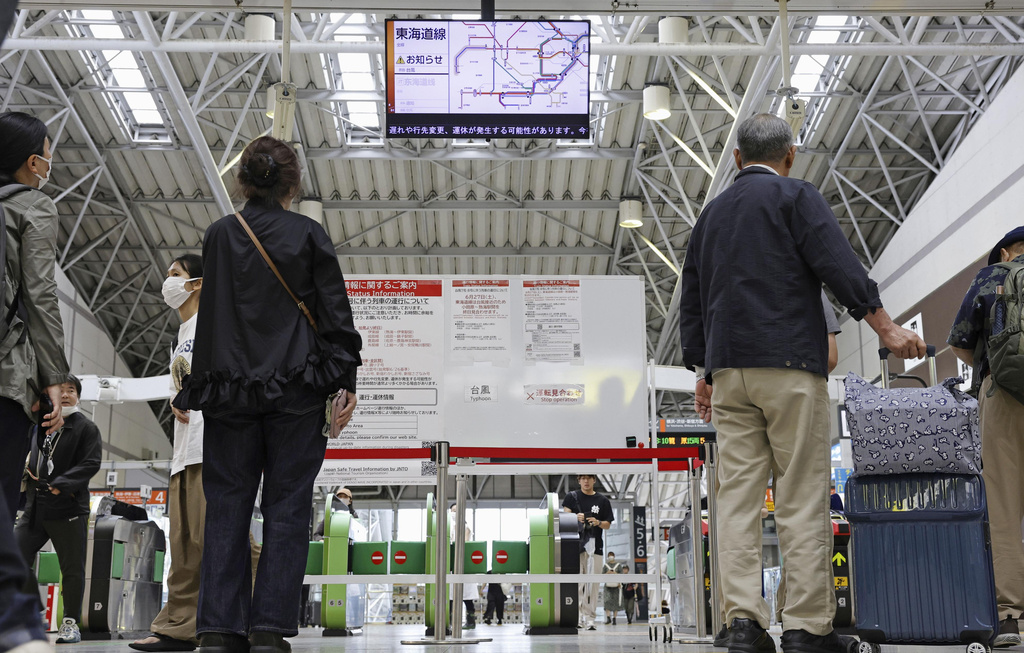 Passengers check train service status as two approaching tropical storms trigger heavy rainfalls, at JR Odawara station in Odawara, Kanagawa Prefecture, Saturday, June 27, 2026. (Kyodo News via AP)