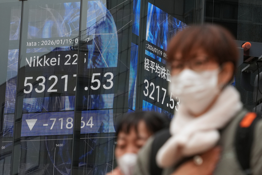 People walk in front of an electronic stock board showing Japan's Nikkei index at a securities firm Monday, Jan. 19, 2026, in Tokyo. (AP Photo/Eugene Hoshiko)