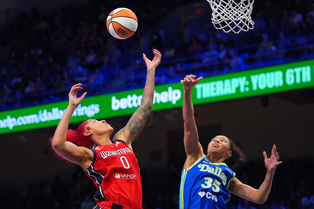Washington Mystics center Shakira Austin (0) and Dallas Wings guard Azzi Fudd (35) jump for a rebound during the second half of a WNBA basketball game in Arlington, Texas, Monday, May 18, 2026. (AP Photo/LM Otero)
