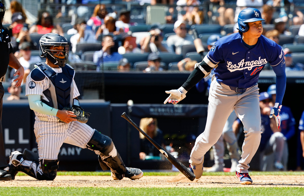 Los Angeles Dodgers' Shohei Ohtani, right, tosses his bat after hitting an RBI single against the New York Yankees during the eighth inning of the first game of a baseball doubleheader, Sunday, July 19, 2026, in New York. (AP Photo/Noah K. Murray)