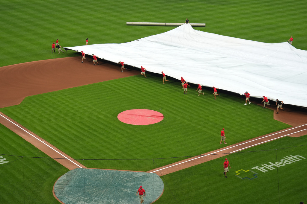 The Cincinnati Reds grounds crew covers the infield during a rain delay before a baseball game against the Cleveland Guardians, Monday, July 27, 2026, in Cincinnati. (AP Photo/Kareem Elgazzar)
