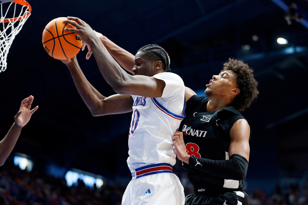Kansas forward Flory Bidunga, left, attempts to score as Cincinnati forward Baba Miller (18) defends during the first half of an NCAA college basketball game, Saturday, Feb. 21, 2026, in Lawrence, Kan. (AP Photo/Colin E. Braley)