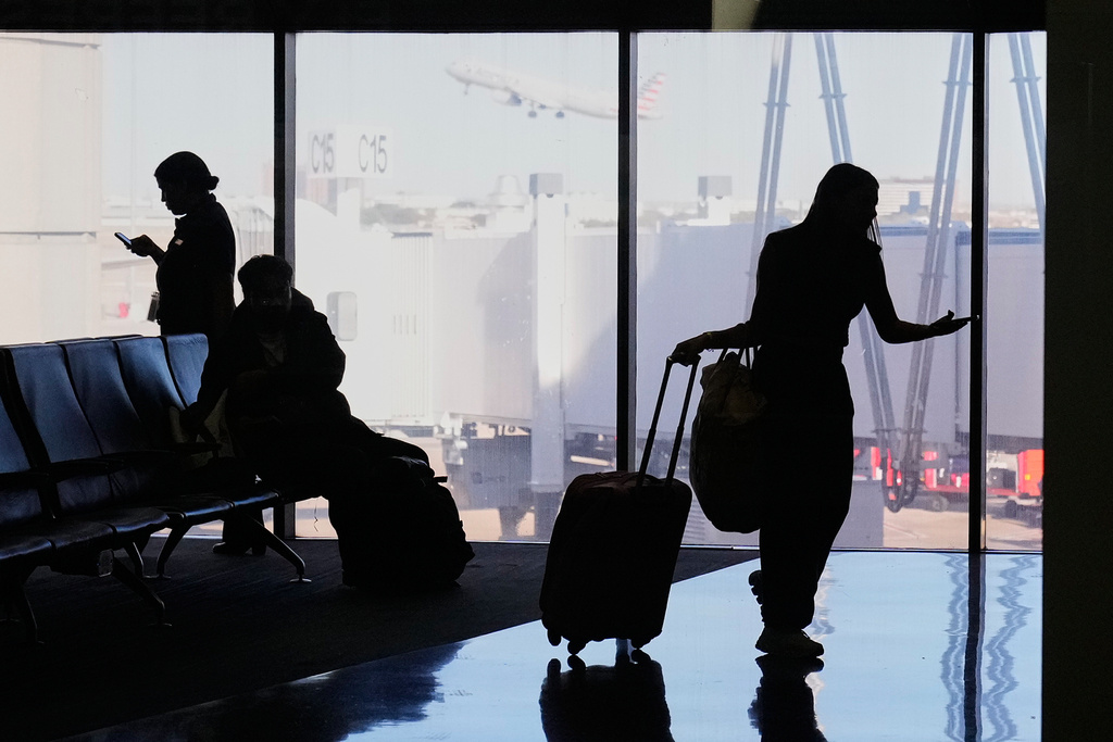 Travelers wait at a gate for their departing flight at the Dallas Fort Worth International Airport, at DFW Airport, Texas, Friday, Nov. 21, 2025. (AP Photo/Tony Gutierrez)
