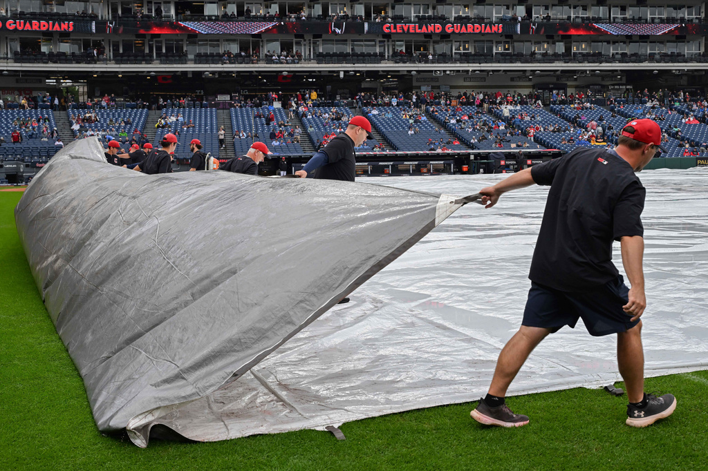 The Progressive Field grounds crew removes a tarp after a rain delay before a baseball game between the Athletics and the Cleveland Guardians, Sunday, Sept. 20, 2026, in Cleveland. (AP Photo/Phil Long)