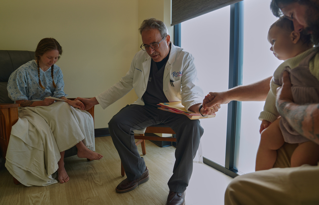 Dr. John Gordon, center, prays with a family before an embryo transfer at Rejoice Fertility, Sunday, Jan. 11, 2026, in Knoxville, Tenn. (AP Photo/Jessie Wardarski)