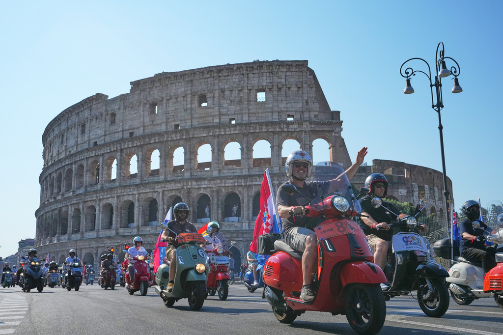 Vespa enthusiasts parade in front of the Colosseum during celebrations for the 80th anniversary of the Vespa scooter, in Rome, Saturday, June 27, 2026. (AP Photo/Alessandra Tarantino)