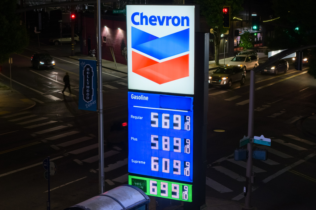 A person walks across the street as a sign for fuel prices is displayed at a gas station on Wednesday, May 6, 2026, in Portland, Ore. (AP Photo/Jenny Kane)