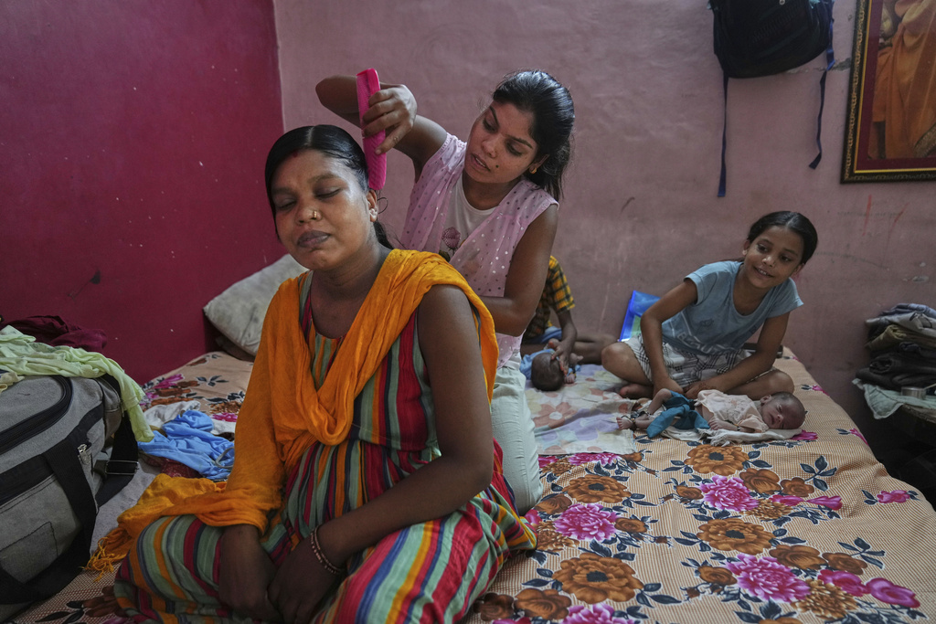 Antima Kumari, center, trained in Care Companion Program (CCP), combs the hair of her sister Lilawati, who delivered twins, at their house in Gurugram, a satellite city of New Delhi, India, on Aug. 8, 2025. (AP Photo/Manish Swarup)