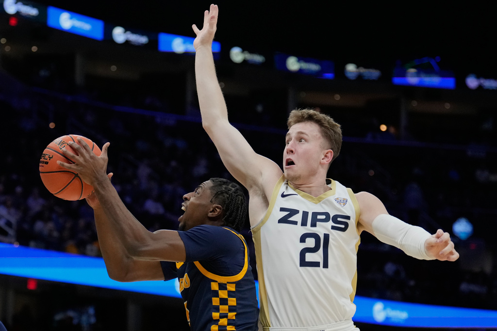 Toledo guard Sonny Wilson, left, goes to the basket past Akron guard Zach Halligan (21) in the first half of an NCAA college basketball game in the championship of the Mid-American Conference tournament, Saturday, March 14, 2026, in Cleveland. (AP Photo/Sue Ogrocki)
