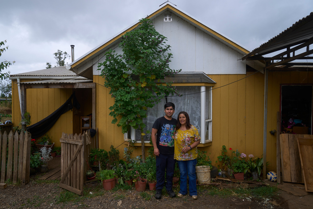 Angelina Cayuqueo, 58, a Mapuche language teacher poses with her son Vicente, 23, outside their home in Pedro Cayuqueo, Chile, Friday, Dec. 12, 2025. (AP Photo/Victor R. Caivano)