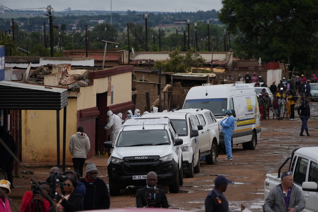 South African police gather at the scene of a mass shooting where gunmen killed nine and injured at least 10 in a pub in Bekkersdal, South Africa, Sunday, Dec. 21, 2025. (AP Photo/ Alfonso Nqunjana)