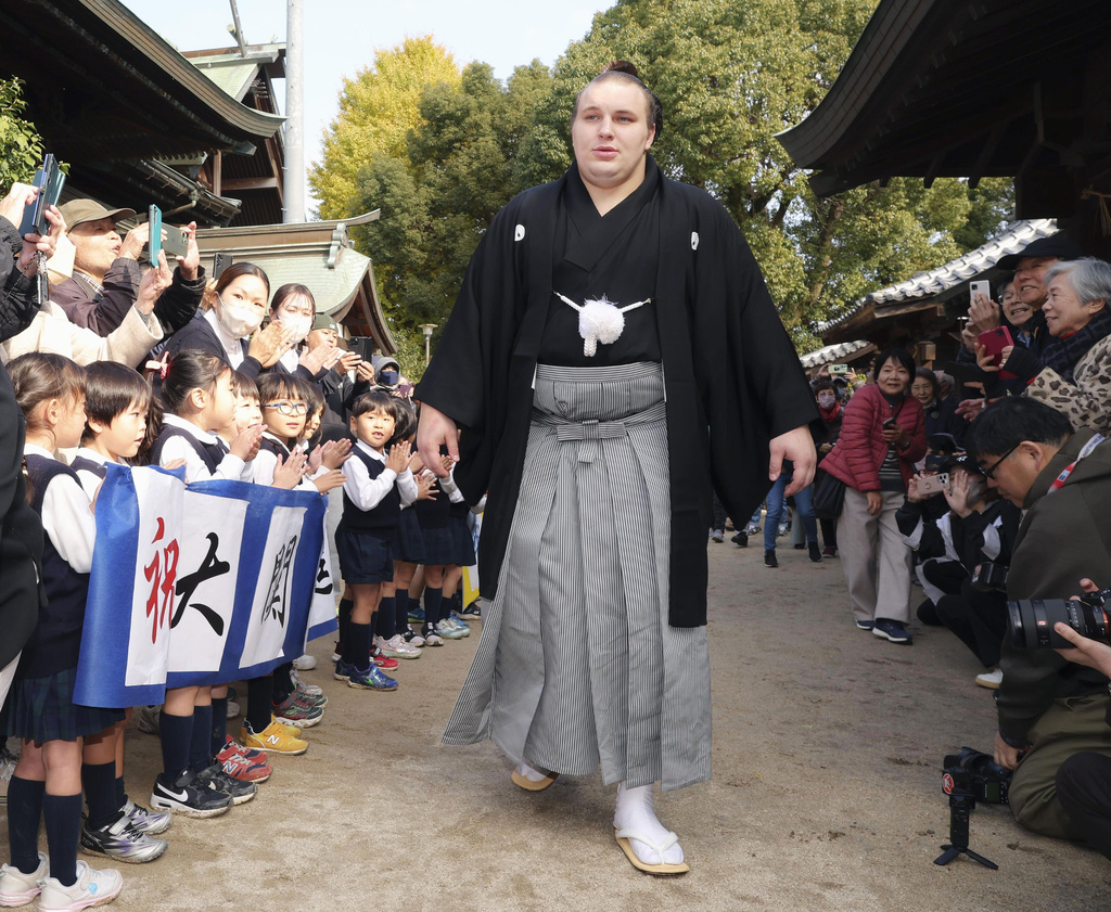 Ukrainian sumo wrestler Aonishiki, center, is celebrated by kindergarteners his promotion to the rank of ozeki in Kurume, Fukuoka prefecture, southern Japan Wednesday, Nov. 26, 2025. (Kyodo News via AP)