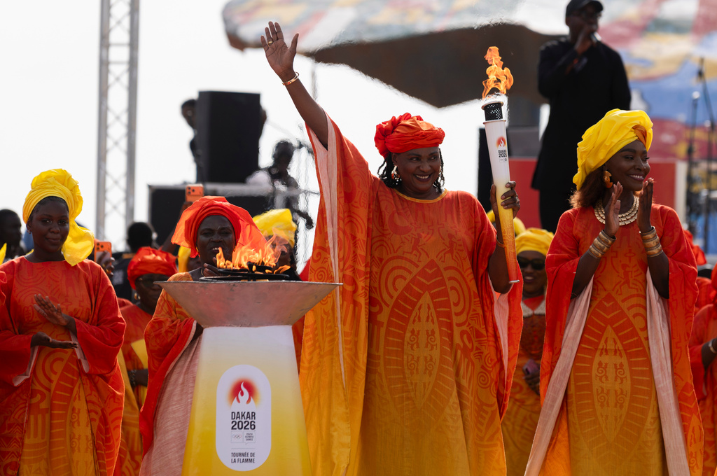 Senegalese basketball legend Mame Maty Mbengue lights a torch from the cauldron during a ceremony ahead of the Dakar 2026 Youth Olympic Games, in Dakar, Senegal, Saturday, Sept. 12, 2026. (AP Photo/Sylvain Cherkaoui)
