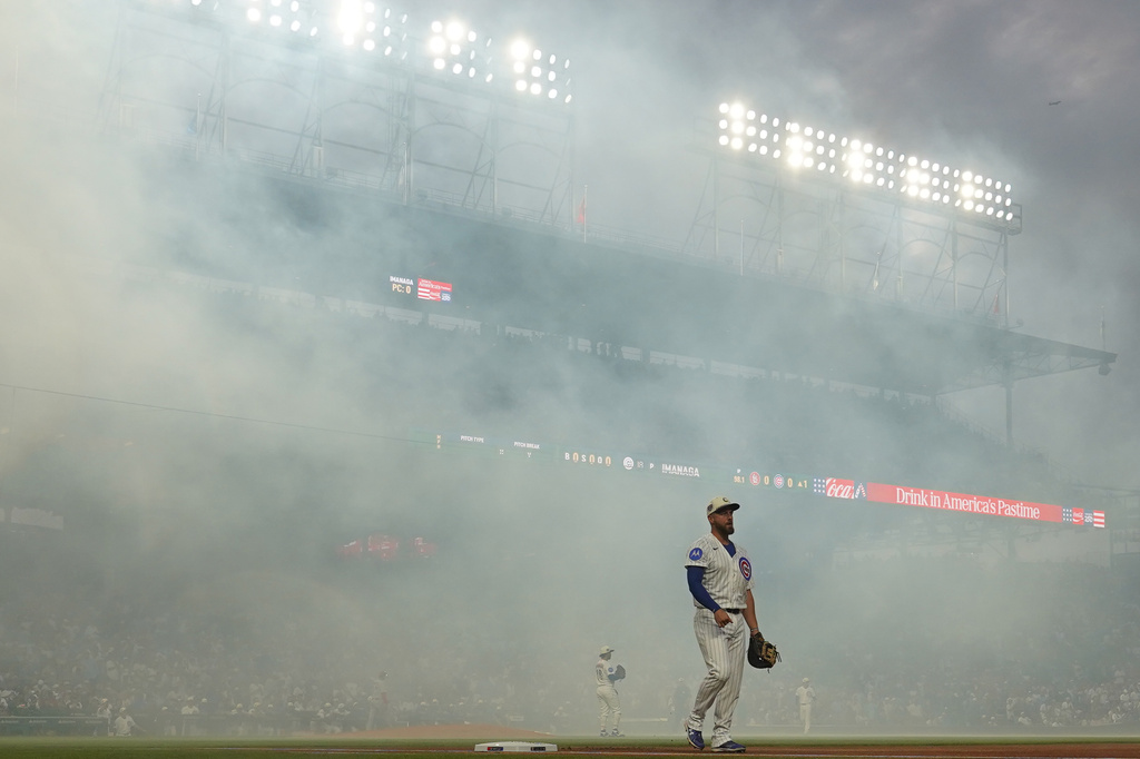 Smoke drifts as Chicago Cubs first baseman Michael Busch looks on after fireworks before a baseball game against the St. Louis Cardinals, Saturday, July 4, 2026, in Chicago. (AP Photo/David Banks)