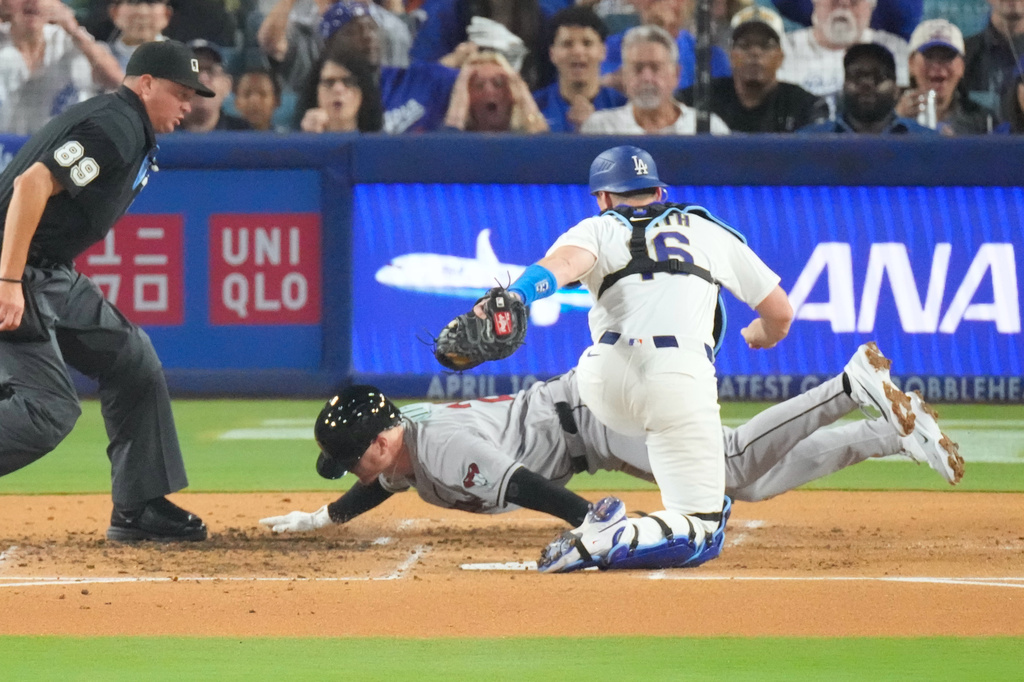 Arizona Diamondbacks' Pavin Smith, center, is tagged out by Los Angeles Dodgers catcher Will Smith as he tries to score on a double by Alek Thomas during the second inning of a baseball game Friday, March 27, 2026, in Los Angeles. (AP Photo/Mark J. Terrill)