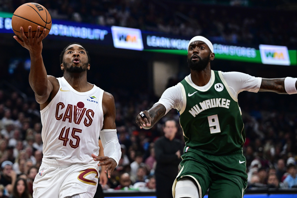 Cleveland Cavaliers guard Donovan Mitchell, left, goes to the basket against Milwaukee Bucks forward Bobby Portis, right, in the first half of an NBA basketball game Sunday, Oct. 26, 2025, in Cleveland. (AP Photo/David Dermer)