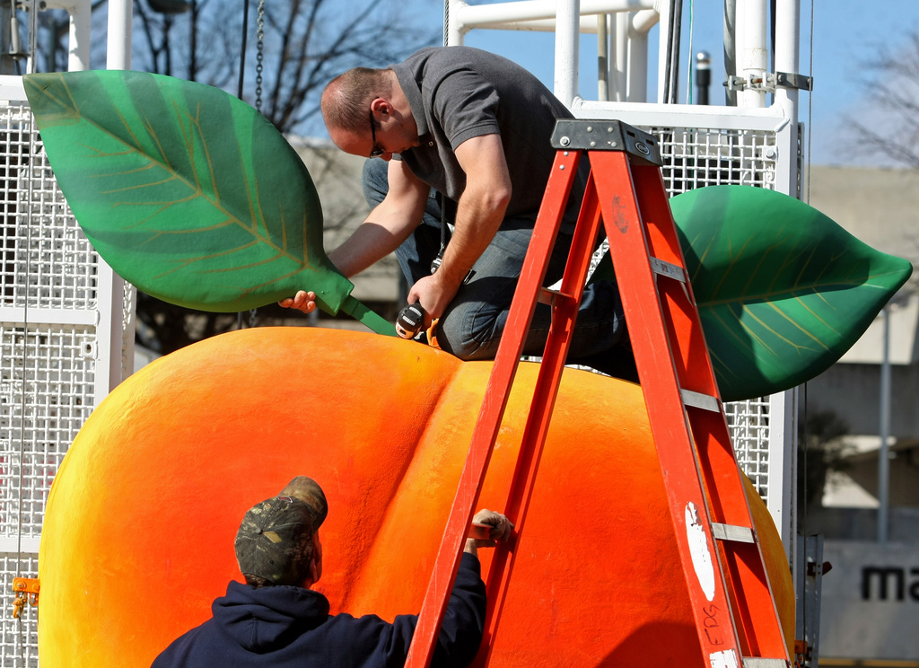 FILE - Gary Seputis, top, and Clint Hornsby, employees of Entertainment Design Group, work on attaching two leaves to the fiberglass and foam Peach in preparation for the 2012 Peach Drop at Underground Atlanta, Friday, Dec. 30, 2011, in Atlanta. ( Jason Getz/Atlanta Journal-Constitution via AP, File)