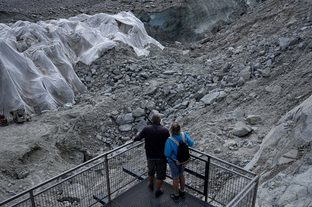 People look at the 'Mer de Glace' glacier as tarpaulins cover the ice cave to prevent it from melting, at the Montenvers station in Chamonix, France, Saturday, Sept. 5, 2026. (AP Photo/Laurent Cipriani)