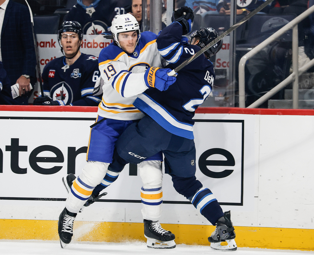 Winnipeg Jets' Dylan DeMelo (2) and Buffalo Sabres' Peyton Krebs (19) collide during first-period NHL hockey game action in Winnipeg, Manitoba, Friday, Dec. 5, 2025. (John Woods/The Canadian Press via AP)