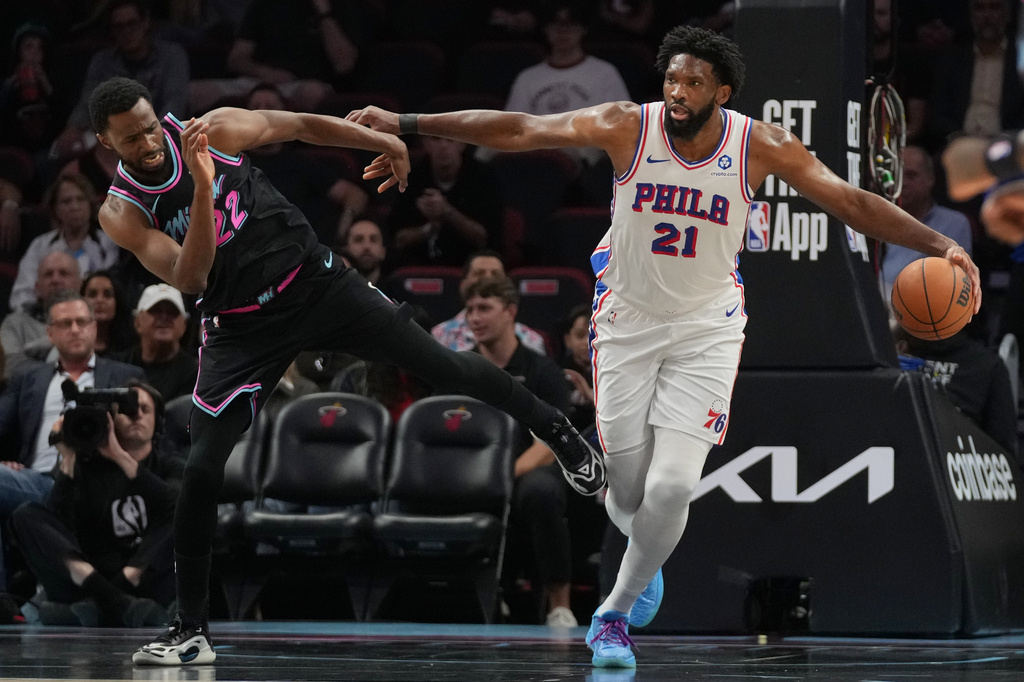 Philadelphia 76ers center Joel Embiid (21) controls the ball as Miami Heat forward Andrew Wiggins (22) defends during the first half of an NBA basketball game, Monday, March 30, 2026, in Miami. (AP Photo/Lynne Sladky)