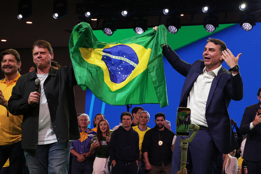 Brazilian Sen. Flavio Bolsonaro, right, and Sao Paulo Gov. Tarcisio de Freitas hold up their country's national flag during the Liberal Party convention where Bolsonaro was confirmed as the party's presidential candidate in Sao Paulo, Saturday, July 25, 2026. (AP Photo/Ettore Chiereguini)