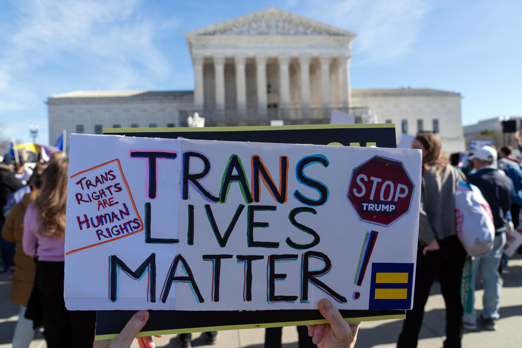 Protesters gather outside the Supreme Court as it hears arguments over state laws barring transgender girls and women from playing on school athletic teams, Tuesday, Jan. 13, 2026, in Washington. (AP Photo/Jose Luis Magana)