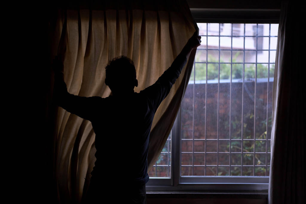 A Tibetan living in exile pulls the curtain before he gives an interview in Kathmandu, Nepal, April 14, 2025. (AP Photo/Niranjan Shrestha)