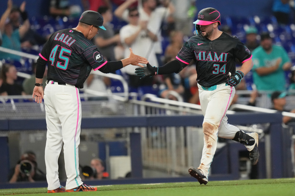 Miami Marlins' Liam Hicks (34) is met by third base coach Blake Lalli (45) after hitting a two run home run during the fifth inning of a baseball game against the Colorado Rockies, Saturday, March 28, 2026, in Miami. (AP Photo/Lynne Sladky)