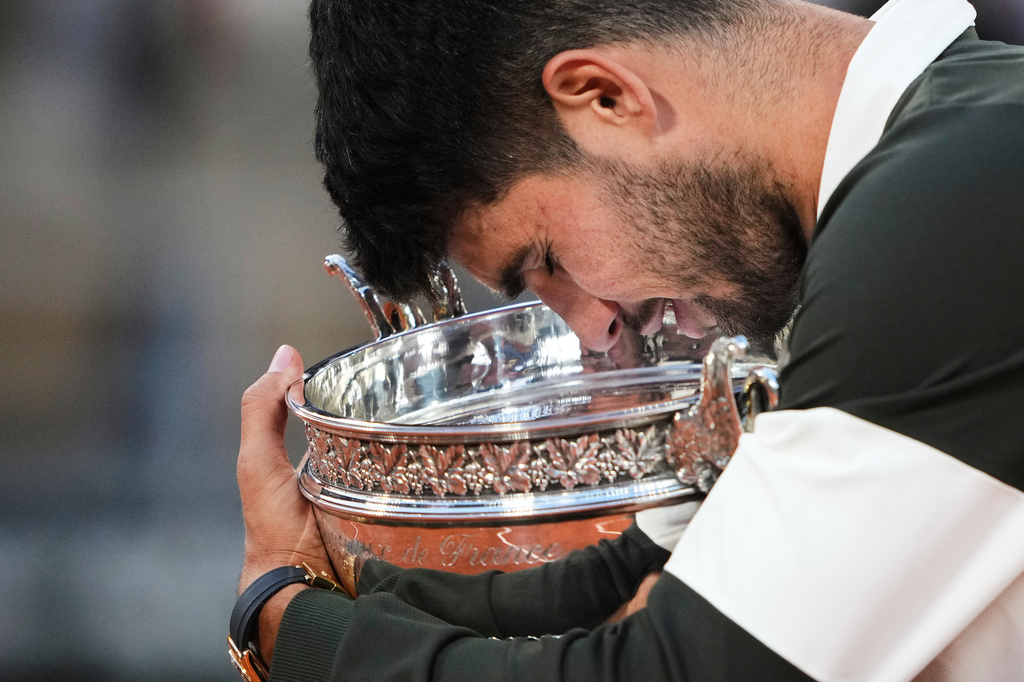 FILE - Spain's Carlos Alcaraz caresses with the trophy after defeating Italy's Jannik Sinner in the final of the French Open tennis tournament, Sunday, June 8, 2025, in Paris. (AP Photo/Lindsey Wasson, File)