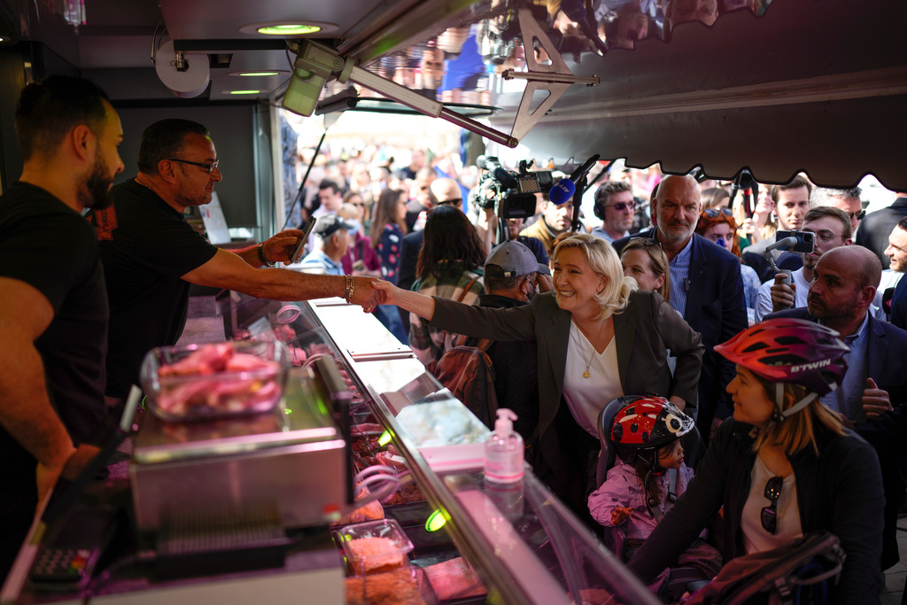 FILE - French far-right leader Marine Le Pen, center, greets people as she campaigns in a market in Pertuis, southern France, Friday, April 15, 2022. (AP Photo/Daniel Cole, File)