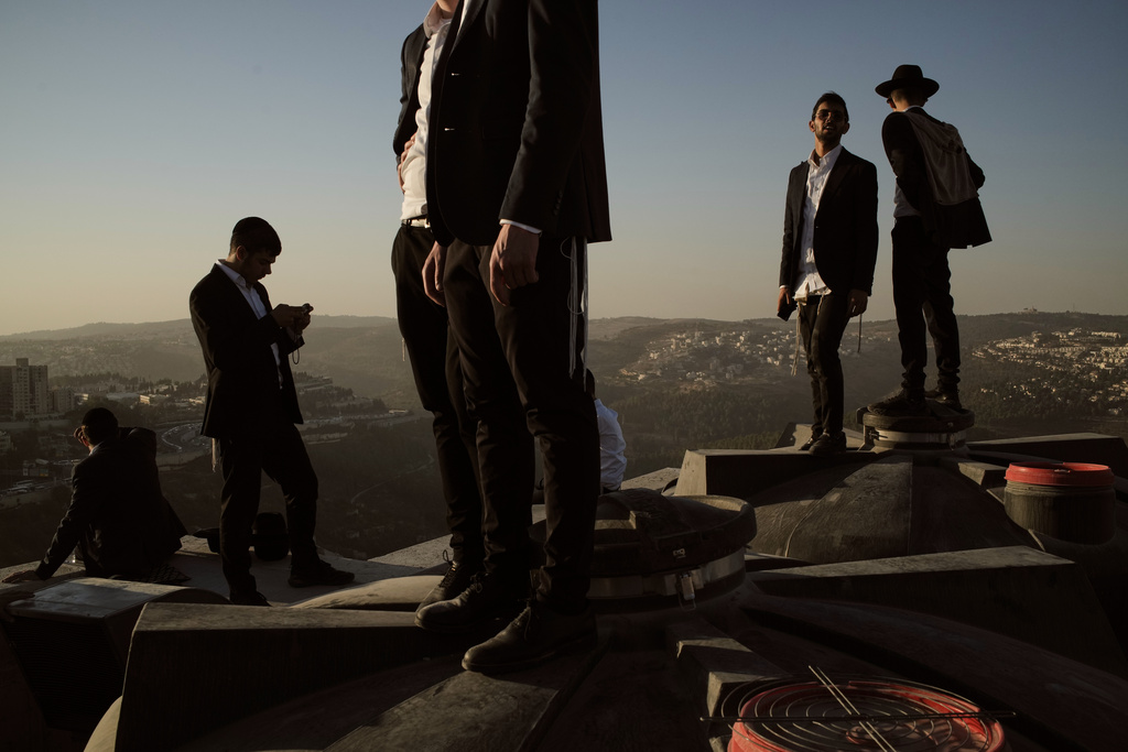 Ultra-Orthodox Jewish men stand of a roof during a rally against plans to force them to serve in the Israeli military, in Jerusalem, Thursday, Oct. 30, 2025. (AP Photo/Leo Correa)
