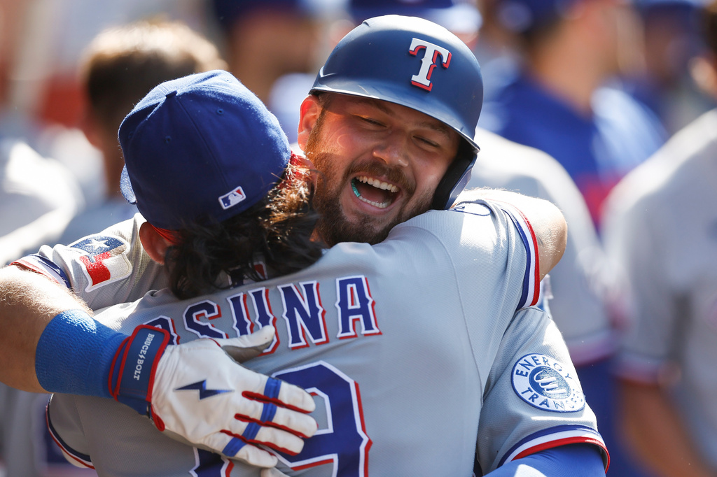 Texas Rangers' Jake Burger, right, is greeted by Texas Rangers' Alejandro Osuna, left, after scoring a home run during the second inning of a baseball game against the Los Angeles Angels, Sunday, May 24, 2026, in Anaheim, Calif. (AP Photo/Caroline Brehman)