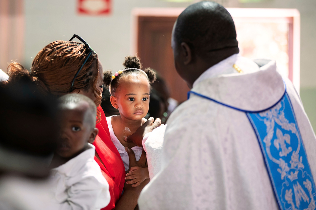 A priest anoints a child with oil during a baptism ceremony at the Roman Catholic Cathedral in Harare, Zimbabwe, Sunday, April 5, 2026. (AP Photo/Aaron Ufumeli)