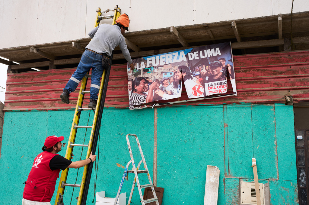 A worker removes a campaign banner of presidential candidate Keiko Fujimori of the Popular Force party placed near a polling station in Lima, Peru, Saturday, June 6, 2026, ahead of Peru's presidential runoff election. (AP Photo/Rodrigo Abd)