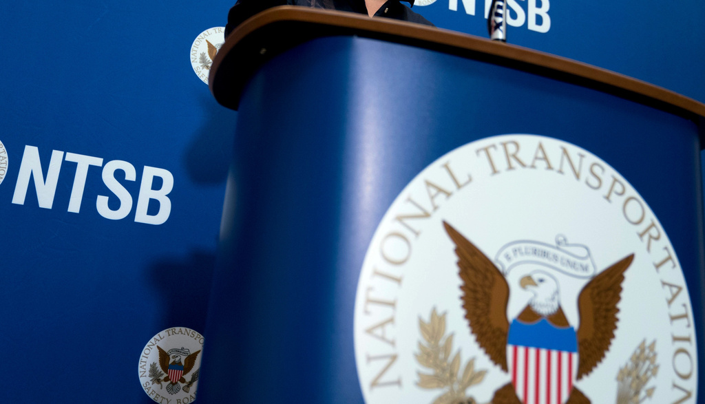 FILE - The National Transportation Safety Board logo and signage are seen at a news conference at NTSB headquarters in Washington, Dec. 18, 2017. (AP Photo/Andrew Harnik, File)