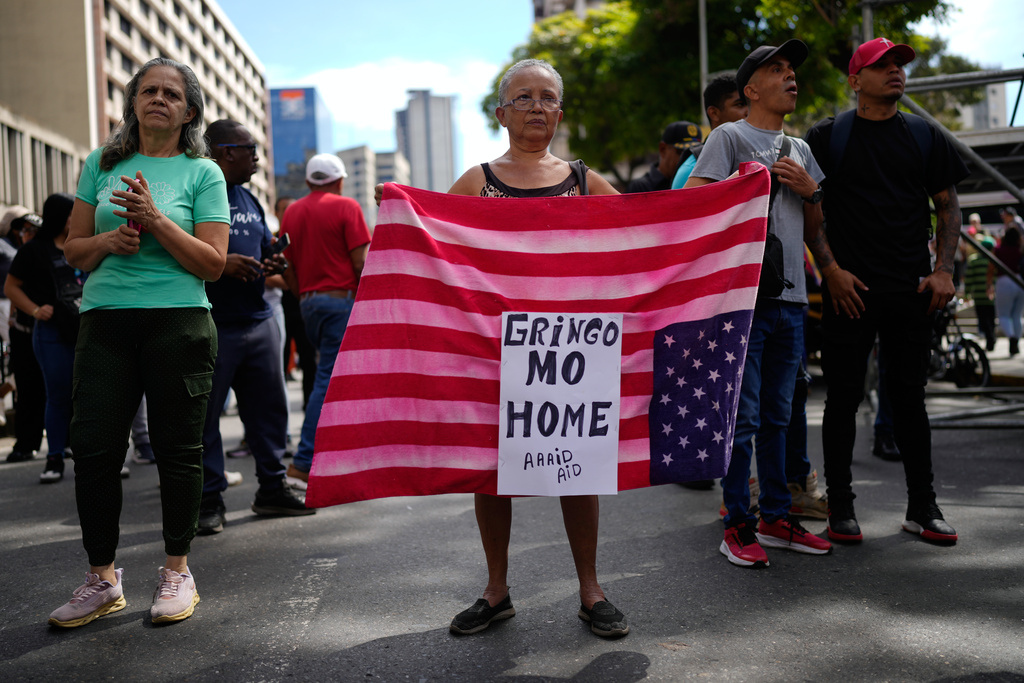 A government supporters displays a U.S. flag in Caracas, Venezuela, Sunday, Jan. 4, 2026. (AP Photo/Ariana Cubillos)